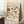 May include: Framed botanical poster with vintage-style floral pattern in warm earth tones including rust, amber, and sage green flowers and leaves on cream background, leaning against white wall corner near wooden side table with coffee cup and cozy knit throw blanket on white textured rug.