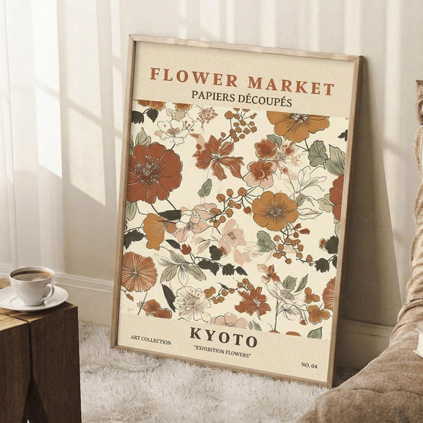 May include: Framed botanical poster with vintage-style floral pattern in warm earth tones including rust, amber, and sage green flowers and leaves on cream background, leaning against white wall corner near wooden side table with coffee cup and cozy knit throw blanket on white textured rug.