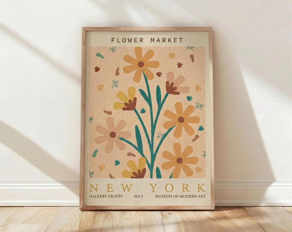May include: Framed botanical poster with vintage cream background featuring stylized flowers in warm orange, yellow, and pink tones with teal green stems and leaves. The print displays "FLOWER MARKET" at top and "NEW YORK" at bottom with gallery-style text. Wooden frame sits on light hardwood floor against white wall with soft natural lighting creating diagonal shadows.