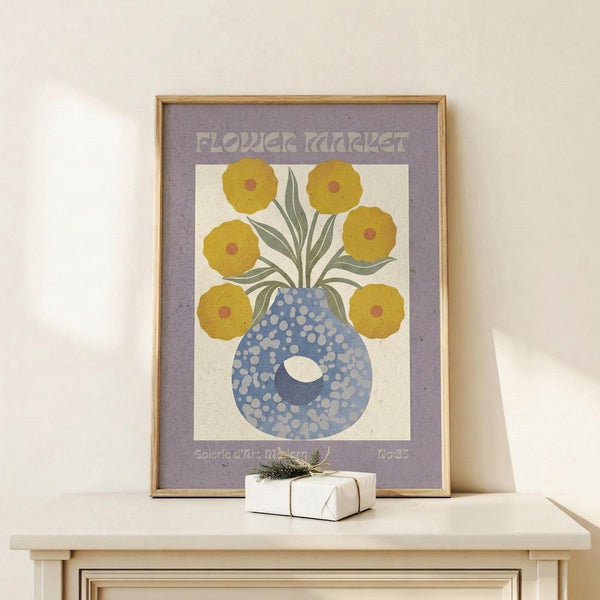 May include: Framed vintage-style poster with purple border featuring yellow flowers with red centers in a blue polka-dotted vase, displayed on light wood console table next to small wrapped gift with greenery, against cream wall with natural lighting