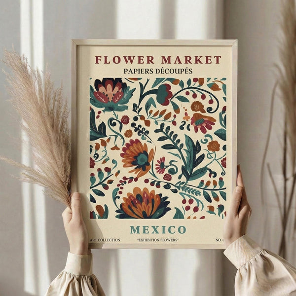 May include: hands holding a framed vintage-style botanical poster featuring colorful folk art flowers in burgundy, teal, and orange tones against cream background. Person wears beige ruffled sleeves, holds dried wheat stems, standing by white curtained window in soft natural lighting.