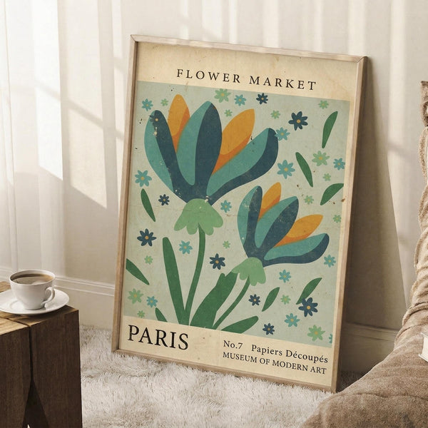 May include: Vintage-style poster with colorful stylized flowers in blues, greens, and orange against cream background, displayed in light wood frame leaning against white wall corner. Small white teacup on wooden block and beige throw blanket visible nearby on white textured rug.