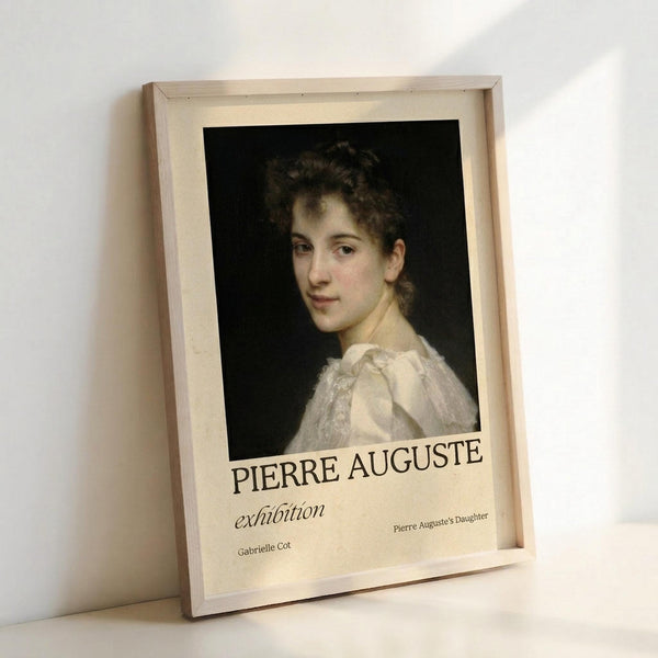 May include: Framed art print leaning against white wall showing classical portrait painting of young woman with curly dark hair in white dress against black background. Cream matting displays "PIERRE AUGUSTE exhibition" text with "Gabrielle Cot" and "Pierre Auguste's Daughter" below. Natural wood frame, soft lighting creates gentle shadows on white surface.
