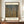 May include: Framed art print of Gustav Klimt's Beech Grove I displayed on a wooden sideboard against cream-colored walls with white molding. The poster features tall birch trees with white bark in an autumn forest with golden-yellow foliage covering the ground. Dark wood frame surrounds the cream-colored print with black text identifying the artwork and Museum of Modern Art. White ceramic vase and stacked books positioned nearby for scale.