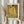 May include: Person in cream ruffled sleeves holding framed art print of Gustav Klimt's "The Kiss" from 1907. Golden artwork shows embracing couple in ornate robes against decorative background. Light wood frame with museum text. Dried pampas grass held in other hand. Neutral curtained background with soft natural lighting.