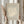 May include: Person in cream sweater holding framed vintage-style art poster featuring white coral or seaweed design on beige background, with dried pampas grass stems in other hand, neutral curtained window backdrop
