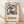 May include: Framed poster with abstract figures in blue, orange and yellow cut-out style artwork displayed against white textured wall on light wood floor. Features dancing forms in Matisse's signature paper collage aesthetic with exhibition text below reading "Discover the Art of Henri Matisse" and museum details. Natural window light creates soft shadows across the minimalist interior setting.