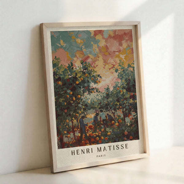 May include: Framed art print featuring a colorful landscape painting with thick brushstrokes, showing trees and foliage in green tones against a vibrant sky with pink, blue, and yellow hues. The print displays "HENRI MATISSE PARIS" text at bottom and sits in a light wooden frame, leaning against a white wall on what appears to be a light surface.