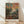 May include: Framed art print featuring an impressionistic landscape painting with vibrant brushstrokes in blues, greens, oranges, and reds depicting foliage and sky. The artwork shows thick paint texture and bold color contrasts typical of post-impressionist style. Text reading "HENRI MATISSE PARIS" appears at bottom. Light wooden frame sits on pale wood flooring against white wall with natural lighting creating soft shadows.