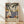 May include: Framed vintage-style poster featuring tropical Mediterranean coastal scene with palm trees, white sailboats on blue water, terracotta buildings, and decorative balustrade. Art displays warm color palette with "MATISSE" text at bottom. Natural wood frame sits on light wooden floor against white wall with window light creating soft shadows.