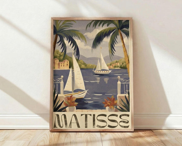 May include: Framed vintage-style poster featuring tropical Mediterranean coastal scene with palm trees, white sailboats on blue water, terracotta buildings, and decorative balustrade. Art displays warm color palette with "MATISSE" text at bottom. Natural wood frame sits on light wooden floor against white wall with window light creating soft shadows.