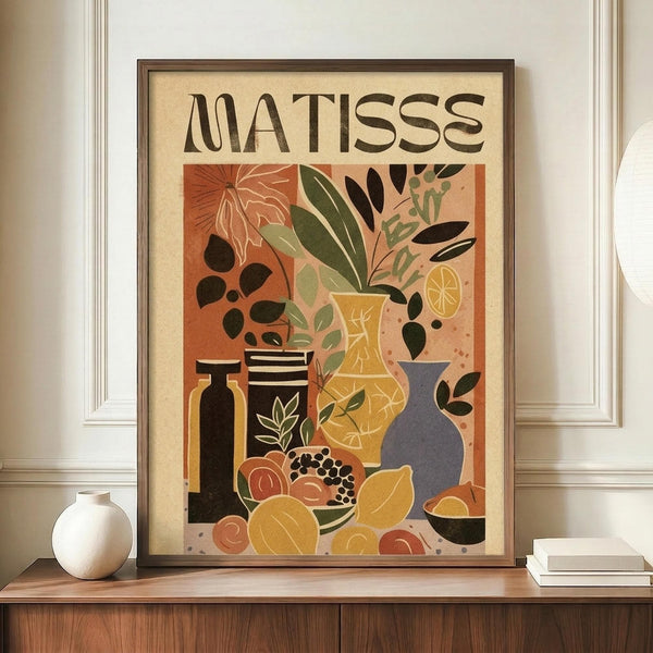 May include: Framed poster featuring Henri Matisse-inspired still life artwork with botanical motifs, ceramic vases, and fruits in warm earth tones of orange, yellow, green, and black. The print displays "MATISSE" text at top and shows various plants, vessels, and organic shapes in a modernist style. Wooden frame sits on credenza beside white ceramic vase and stacked books in neutral-toned room with white walls and crown molding.