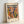 May include: Framed art print featuring abstract colorful shapes in Matisse's cut-out style with bold text "MATISSE" at top. Artwork displays flowing organic forms in vibrant blues, oranges, greens, yellows and pink against cream background. Print includes "Musées Matisse," "Tribute to a Master," "06200 NICE, FRANCE" and social media text. Light wood frame sits against white wall creating soft shadows.