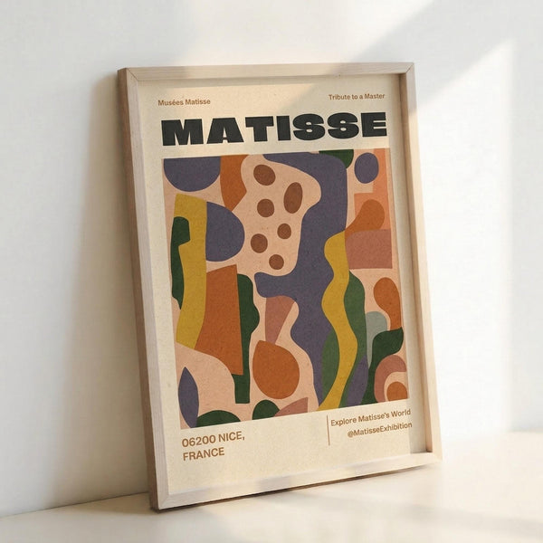May include: Framed art print featuring abstract colorful shapes in Matisse's cut-out style with bold text "MATISSE" at top. Artwork displays flowing organic forms in vibrant blues, oranges, greens, yellows and pink against cream background. Print includes "Musées Matisse," "Tribute to a Master," "06200 NICE, FRANCE" and social media text. Light wood frame sits against white wall creating soft shadows.