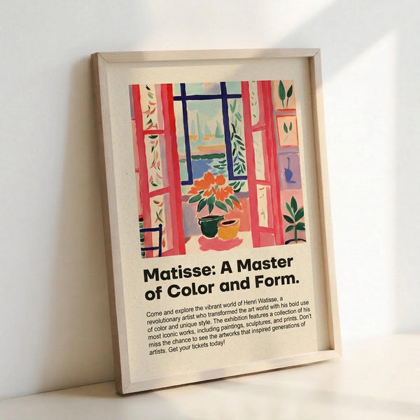 May include: Framed poster print leaning against white wall showing colorful Matisse-style interior scene with red window frames, orange flowers in vase, green plants, and blue water view. Features exhibition text "Matisse: A Master of Color and Form" with descriptive paragraph below artwork. Light wood frame on white surface with soft lighting.