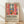 May include: Framed poster print featuring Henri Matisse-inspired artwork of an interior scene with coral red French doors opening to a window view, orange flowers in pottery, leafy plants, and vibrant fauve-style colors. Wooden frame leaning against white wall on light wood flooring with natural window shadows. Exhibition-style poster with black text describing the artist's revolutionary use of color and form.