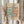 May include: Person in cream blouse holding framed Matisse exhibition poster featuring abstract coral and teal organic shapes on cream background, displayed with dried pampas grass against white curtained window in soft natural lighting