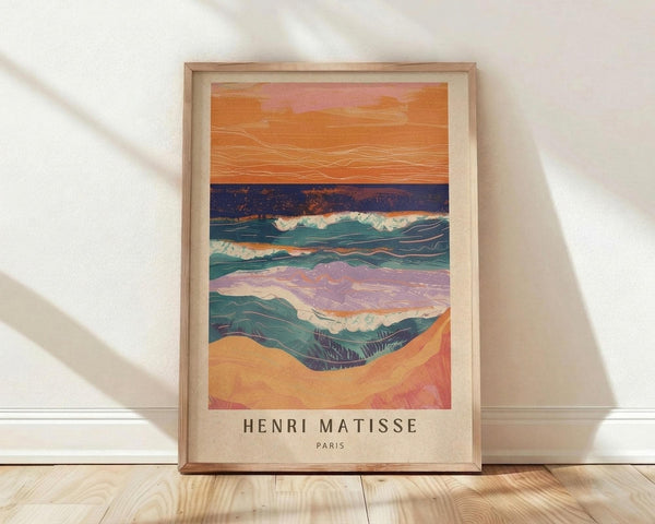 May include: Framed art print featuring abstract landscape with layered horizontal bands in warm oranges, deep blues, teal waves with white foam, and purple-pink sections, displayed in light wood frame against white wall on wooden floor with natural lighting creating diagonal shadows