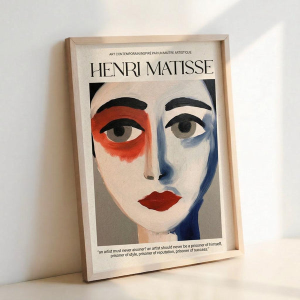 May include: Framed art print featuring an abstract portrait in Matisse's style with bold brushstrokes, showing a face with one red eye area, one blue side, dark eyebrows, and red lips against a cream background. The print displays "HENRI MATISSE" at the top with French text and an inspirational quote at the bottom. Light wooden frame leaning against white wall with natural lighting creating soft shadows.