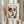 May include: Person in cream ruffled blouse holding framed art print featuring stylized portrait with asymmetrical face design in red, blue, and neutral tones. Modern minimalist frame against soft curtained background. Person also holds dried pampas grass stems. Contemporary art poster with French text and artist quote below the portrait illustration.