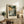 May include: Framed art print displaying a dramatic seascape with stormy clouds, rocky cliffs, and turbulent ocean waves in muted green, gold, and gray tones. The poster features "HENRI MATISSE" and "PARIS" text below the artwork. Shown leaning against white wall on rustic wooden sideboard alongside fern plant, ceramic vase, books, and table lamp in warm-toned living room setting.