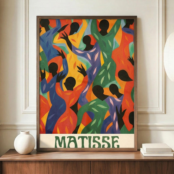 May include: Colorful abstract art poster in dark frame showing silhouetted dancing figures in vibrant blues, greens, oranges, and yellows with "MATISSE" text at bottom. Displayed on wooden sideboard next to white ceramic vase and stacked books in elegant room with white walls and crown molding.