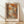 May include: Framed art print featuring an autumn forest scene with orange and brown foliage, dark tree trunks, and a misty pathway. The artwork shows painterly brushstrokes in warm earth tones with "HENRI MATISSE PARIS" text below the image. Natural wood frame sits against white wall on light wooden floor with soft sunlight shadows.