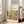 May include: Framed art poster displaying a vibrant Matisse-style garden scene with colorful abstract foliage, trees, and botanical elements in yellows, greens, blues, and coral tones. The poster features text reading "DISCOVER THE BEAUTY OF MATISSE'S ART" and "MODERN HOME DECOR" on cream background. Shown leaning against white wall next to beige upholstered chair in bright, naturally-lit room with white wood floors.