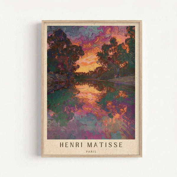 May include: Framed art print displaying a vibrant landscape scene with trees silhouetted against a colorful sunset sky in purples, oranges and yellows, reflected in water below. The image features bold, expressive brushstrokes and rich jewel tones throughout. Text reads "HENRI MATISSE PARIS" at bottom. Light wooden frame against white wall background.