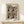 May include: Framed art print with colorful polka dot pattern in blues, oranges, and earth tones displayed on light wood shelf against cream wall. Print features overlapping circles with dotted textures in Kusama's signature style, showing "OSAKA 1988" text. Small wrapped gift box with twine sits beside the thin wooden frame.