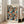 May include: Framed art print leaning against white wall next to beige upholstered chair in bright living room. Poster features colorful polka dot pattern with overlapping circles in blues, oranges, greens, and earth tones on black background. Text reads "YAYOI KUSAMA" and "OSAKA 1988" at top, Japanese characters at bottom. Light wood frame, natural lighting from large windows.