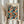 May include: Person holding framed poster featuring colorful polka dot pattern in blues, oranges, reds, and yellows on black background. Text reads "YAYOI KUSAMA" and "OSAKA 1988" with Japanese characters below. Light wood frame against neutral curtained background with dried pampas grass visible on left side.