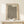 May include: Framed poster with black polka dot pattern on cream background, featuring "YAYOI KUSAMA" and "TOKYO 1992" text at top, displayed on light wood console table against white wall. Small wrapped gift box with twine and greenery sits beside the wooden frame.