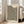 May include: Framed beige poster with black polka dot pattern leaning against white wall next to beige upholstered chair. Print features bold black text at top reading "YAYOI KUSAMA" and "TOKYO 1992" with dense field of irregular black dots covering most of the design. Japanese text appears at bottom. Natural wood frame, bright room with large windows casting soft shadows on wooden floor.