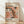 May include: Framed exhibition poster featuring abstract organic shapes in coral, peach, and cream tones with black and white polka dot patterns. Text reads "Yayoi Kusama Tokyo 1998" and "22 - April 1986" with Japanese characters. Natural wood frame leaning against white textured wall on light wooden floor with soft shadows.