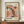 May include: Framed abstract art poster with organic coral and black spotted shapes on cream background, displayed on wooden sideboard next to white ceramic vase and books. Wood frame complements neutral wall paneling and warm interior styling.