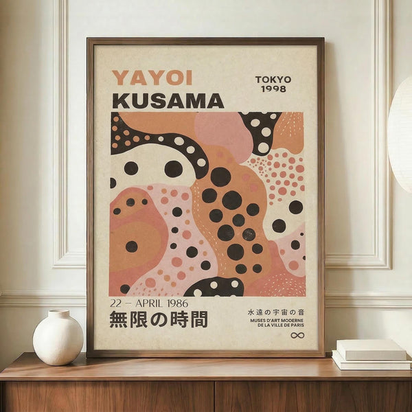 May include: Framed abstract art poster with organic coral and black spotted shapes on cream background, displayed on wooden sideboard next to white ceramic vase and books. Wood frame complements neutral wall paneling and warm interior styling.