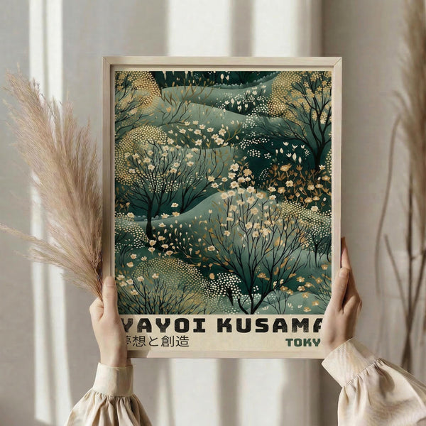 May include: Person holding framed art print featuring abstract botanical pattern in sage green and cream tones with dotted textures, small flowering branches, and Japanese text at bottom. Natural wood frame, shown with dried pampas grass against soft beige curtains in bright natural lighting.