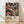 May include: Framed art poster featuring abstract swirling patterns in vibrant colors including orange, purple, blue, and yellow with polka dot elements. Text reads "Yayoi Kusama" with Japanese characters and "Musee d'Art Moderne de la Ville de Paris" below colorful psychedelic design. Natural wood frame displayed on light wooden floor against white fabric backdrop with soft shadows.