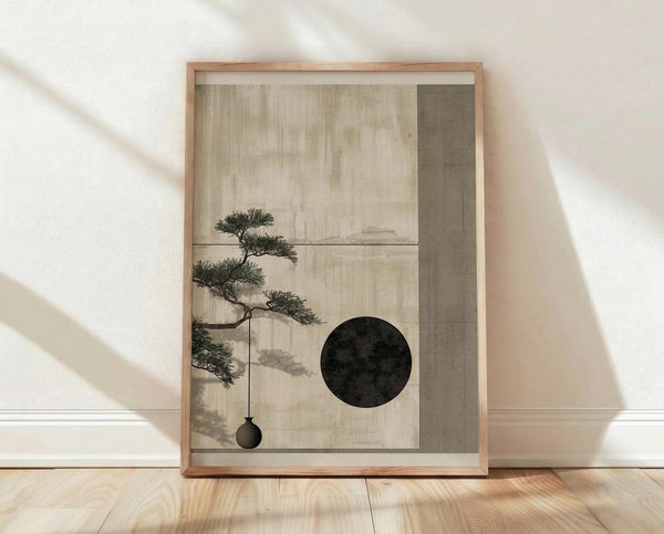May include: Framed minimalist botanical artwork leaning against white textured wall on light wood flooring. Natural wood frame contains muted sage and cream artwork featuring delicate bonsai tree branch with hanging ornament and dark circular moon shape. Soft natural lighting creates diagonal shadows across the peaceful interior scene.