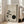 May include: Framed minimalist artwork leaning against white wall beside beige sofa, featuring zen-style illustration of pine tree branch with hanging ornament and dark circular moon shape on textured neutral background, displayed in light wood frame on hardwood floor in bright living room setting