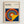 May include: Framed Bauhaus poster with geometric design featuring colorful concentric circles in red, yellow, blue, and orange on navy background with yellow triangle overlay. Light wood frame against white textured wall. Clean minimalist presentation showcasing modernist art style with bold primary colors and abstract circular pattern.