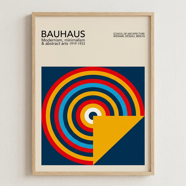 May include: Framed Bauhaus poster with geometric design featuring colorful concentric circles in red, yellow, blue, and orange on navy background with yellow triangle overlay. Light wood frame against white textured wall. Clean minimalist presentation showcasing modernist art style with bold primary colors and abstract circular pattern.