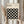 May include: Hands holding a framed Bauhaus-inspired poster with black circular overlapping pattern on cream background, displayed against white curtains with dried pampas grass visible to the left. The geometric design features intersecting circles creating diamond shapes between them. Light wood frame complements the minimalist aesthetic.
