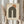 May include: Person holding framed Bauhaus-inspired poster with geometric design featuring dark green concentric arches and terracotta circle on cream textured background, displayed next to dried pampas grass in neutral toned room setting