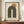 May include: Framed minimalist poster featuring a large dark green rainbow arch with cream stripes and a terracotta sun circle above, displayed on wooden sideboard next to white ceramic vase and books in neutral-toned room with paneled walls
