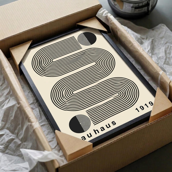 May include: Black and white geometric poster with curved concentric lines forming abstract shapes, displayed in black frame inside cardboard shipping box with protective wrapping. Minimalist Bauhaus-style design on cream background with "1919 bauhaus" text and small circular elements in corners.