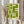 May include: Person holding framed geometric abstract poster with olive green interlocking rectangular shapes on cream background, styled with dried pampas grass in neutral minimalist interior setting with white curtains and beige clothing