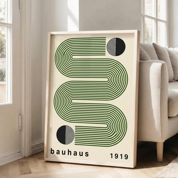 May include: Framed poster with green wavy lines and black half-circles on cream background, displayed in bright living room corner next to beige armchair and large windows with natural light streaming in