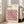 May include: Framed Bauhaus poster with geometric cube pattern in pink, orange, black and cream colors, displayed on light wooden floor next to beige upholstered chair. Natural light streams through white-framed windows in minimalist room setting. The artwork features three-dimensional cubic tessellation design with modernist typography at top.